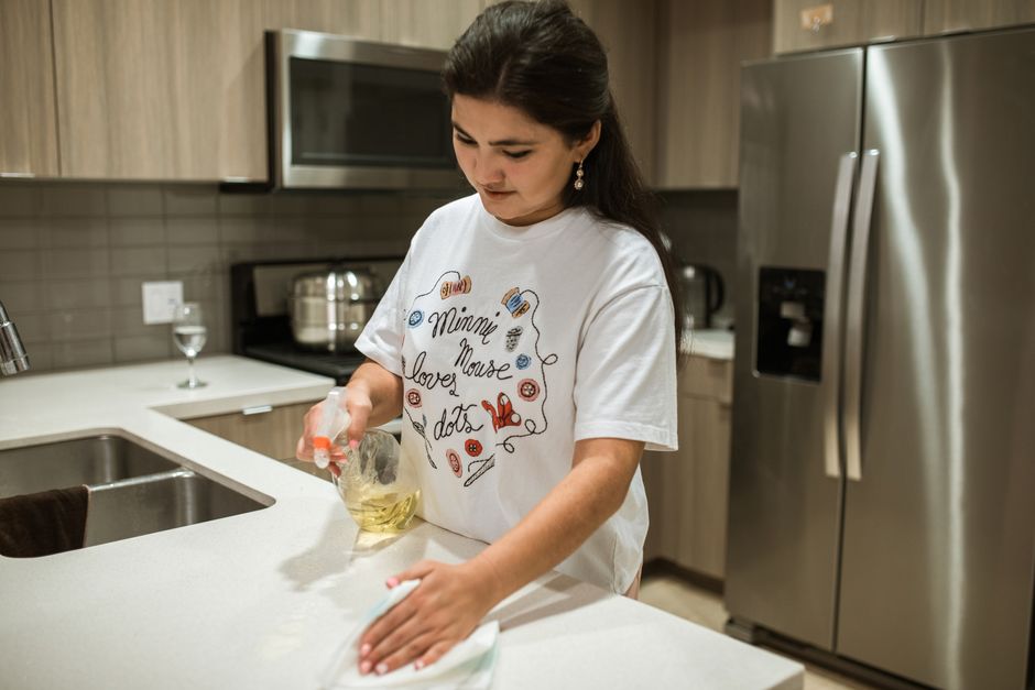 A professional wiping down a modern kitchen counter